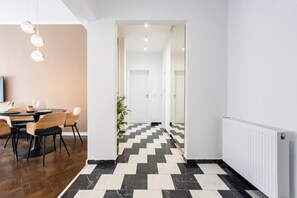 Ein modernes Interieur mit Essbereich, einem Flur mit Schachbrettmuster und einem weißen Heizkörper.