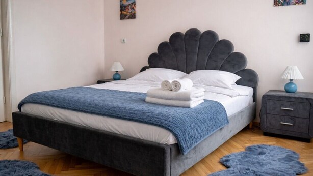 A bedroom with a bed, bedside tables, and a blue rug. - Luxury l Apartment | Radisson | Calea Victoriei (Bucharest)