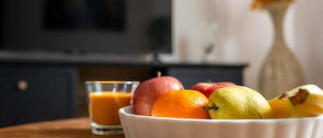 A bowl of fruit on a table with a glass of orange juice.