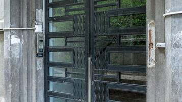 Une grande porte en métal ouvragée, surmontée d’un panneau de verre, le tout intégré à une structure en pierre.