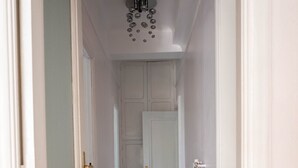 A hallway with a patterned floor, white walls, and a door at the end. - Luxury l Apartment | Radisson | Calea Victoriei (Bucharest)