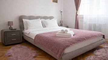 Une chambre à coucher avec un lit, une table de chevet, une lampe et une fenêtre avec des rideaux.