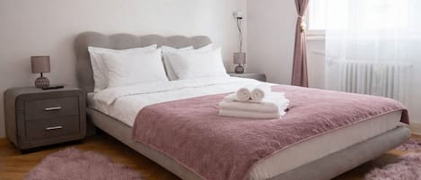 A bedroom with a bed, a nightstand, a lamp, and a window with curtains.
