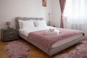 Une chambre à coucher avec un lit, une table de chevet, une lampe et une fenêtre avec des rideaux.