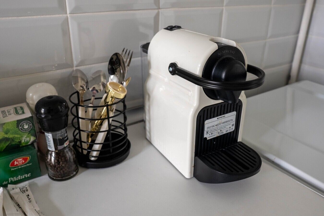 A kitchen with a coffee maker, a spice rack, and a box of tea.