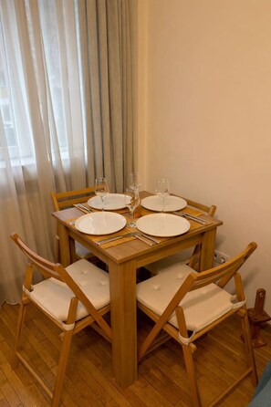 Ein Esstisch mit vier Stühlen, jeweils mit gepolsterten Sitzflächen, gedeckt für vier Personen mit weißen Tellern und Weingläsern.