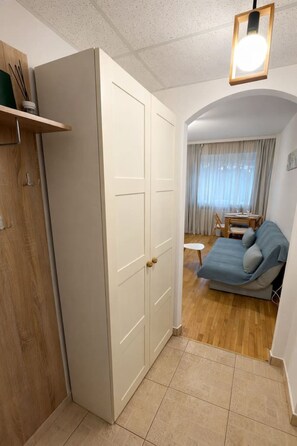 Ein gemütlicher Raum mit Kleiderschrank, Sofa, kleinem Tisch und einem blickdichten Fenster.