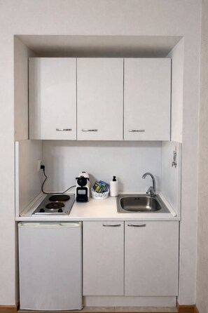 Eine kompakte Küchenzeile mit einem Gasherd, einem Spülbecken und einem kleinen Kühlschrank.