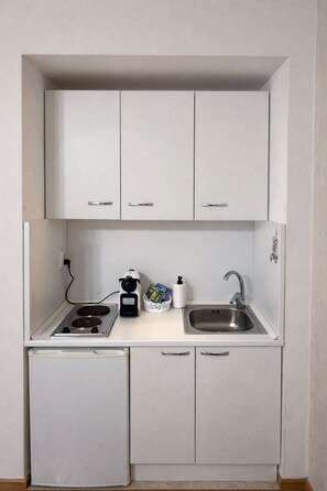 A compact kitchenette with a gas stove, a sink, and a small refrigerator. - Downtown Comfort Studio - Stay different (Bucharest)