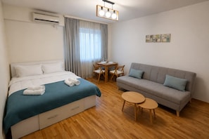 A hotel room with a bed, a sofa, a dining table with chairs, and a small round table. - Downtown Comfort Studio - Stay different (Bucharest)