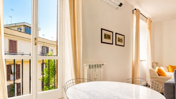 Ein Zimmer mit einem runden Marmortisch, einem Heizkörper und einem Fenster mit Vorhängen.