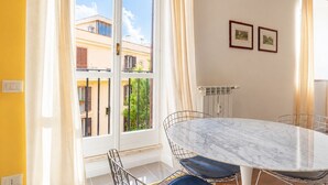 Ein Zimmer mit einem großen Fenster, einem Esstisch mit Stühlen und zwei gerahmten Bildern an der Wand.