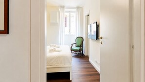 Ein Hotelzimmer mit einem Bett, einem Sessel, einem Fernseher und einer Tür.