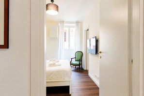 Ein Hotelzimmer mit einem Bett, einem Sessel, einem Fernseher und einer Tür.