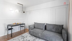A modern living room with a grey sofa, a dining table with chairs, and a pendant light. - Beautique Apartament Panoramic View | Central (Bucharest)
