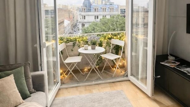 A modern apartment with a balcony, a sofa, a small table, and chairs. - Beautique Apartament Panoramic View | Central (Bucharest)