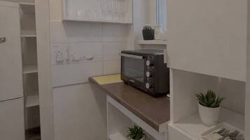 Une cuisine compacte équipée d’un grille-pain encastré, d’une petite fenêtre et d’une plante en pot.