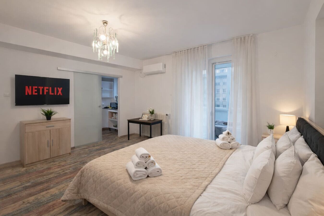 Une chambre d’hôtel équipée d’un lit, d’une télévision, d’un bureau, d’une chaise, d’une fenêtre et d’une porte.