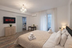 Ein Hotelzimmer mit Bett, Fernseher, Schreibtisch, Stuhl, Fenster und Tür.