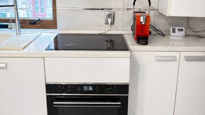A modern kitchen with white cabinetry, a black dishwasher, a red coffee machine, and a stainless steel sink. - Modern Studio Apartment | Comfortable & Center (Bucharest)
