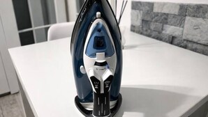 Eine moderne Küche mit einem weißen Tisch, einem blau-weißen Bügeleisen und einer gefliesten Spritzschutzwand.