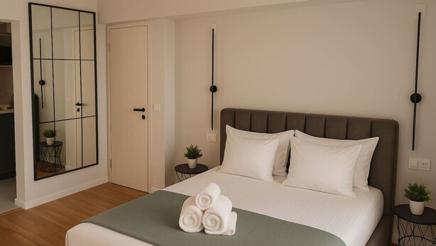 A bedroom with a bed, a mirror, a bedside table with a plant, and a door. - Downtown Loft with Panoramic View (Bucharest)