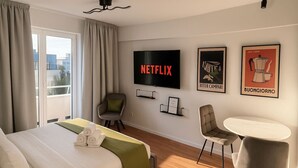 A hotel room with a bed, a TV, a chair, a table, and artwork on the wall. - Downtown Loft with Panoramic View (Bucharest)
