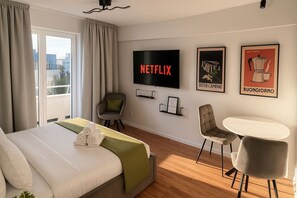 Ein Hotelzimmer mit einem Bett, einem Fernseher, einem Sessel, einem Tisch und Bildern an der Wand.