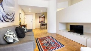 En moderne stue med sofa, fjernsyn og et mønstret tæppe.