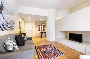 Ein modernes Wohnzimmer mit Sofa, Fernseher und einem gemusterten Teppich.