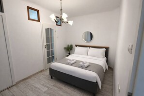 Una camera da letto moderna con un letto, un lampadario, uno specchio rotondo e una porta con pannelli di vetro sabbiato.