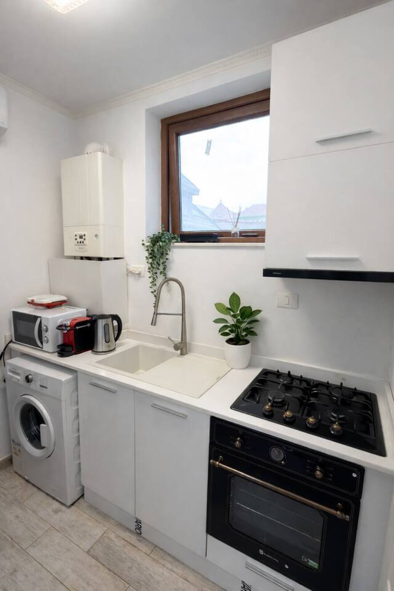Une cuisine compacte équipée d’un lave-linge, d’un four à micro-ondes, d’un évier et d’une cuisinière.