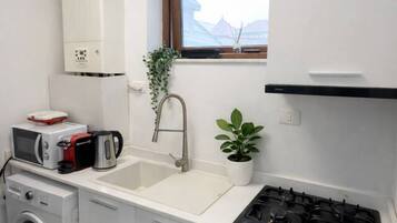 Une cuisine compacte équipée d’un lave-linge, d’un four à micro-ondes, d’un évier et d’une cuisinière.