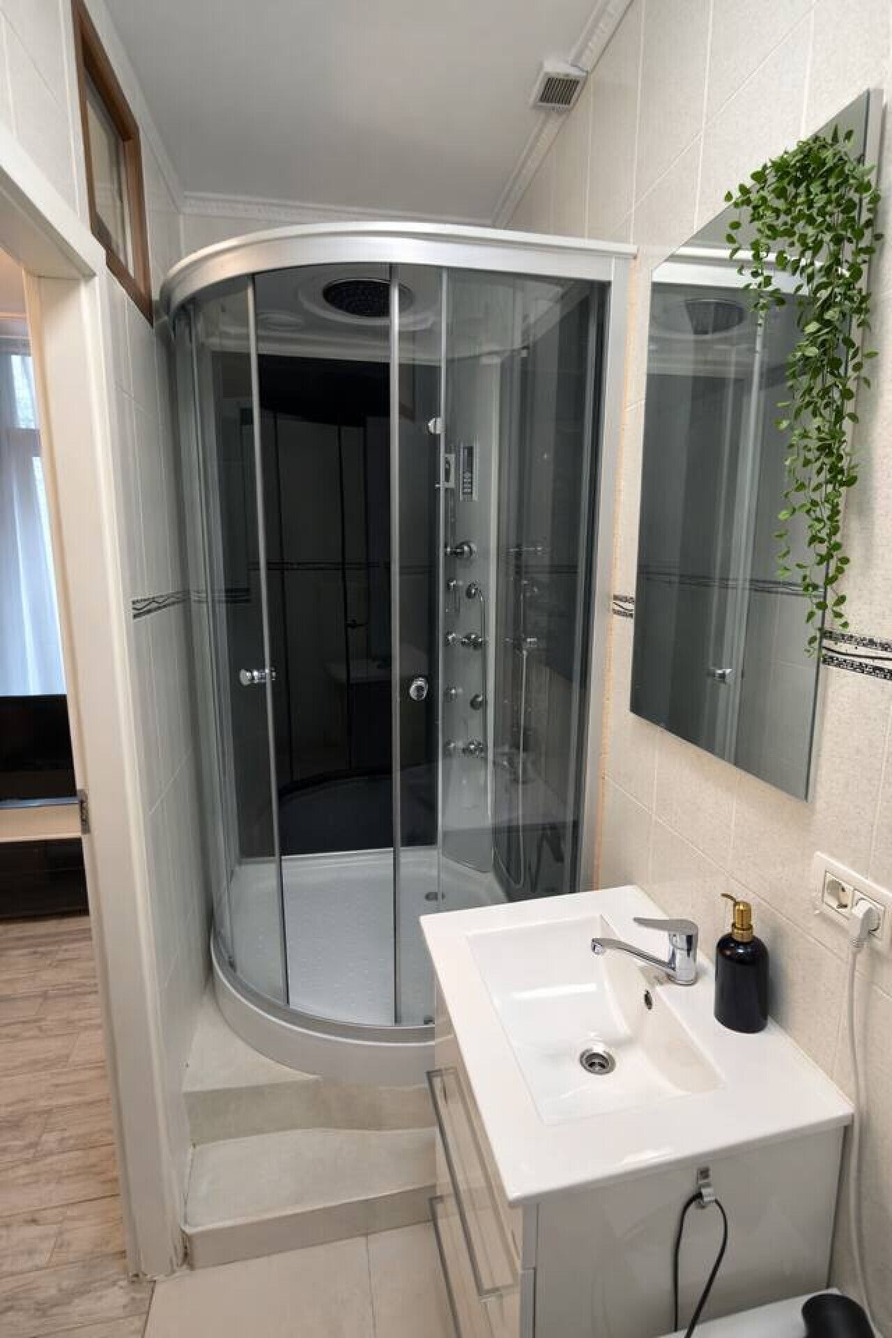 Une salle de bain moderne avec une douche à l’italienne en verre, un lavabo blanc et un miroir.