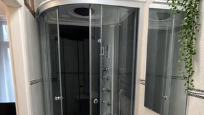 A modern bathroom with a glass shower enclosure, a white sink, and a mirror. - LightHouse Apartment | 2 BedRoom Apartment (Bucharest)