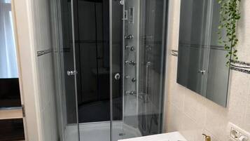 Une salle de bain moderne avec une douche à l’italienne en verre, un lavabo blanc et un miroir.