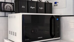 Un microondas Samsung sobre una encimera blanca, con un refrigerador blanco debajo.
