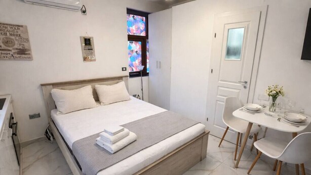 Un dormitorio con cama, mesita de noche y una pequeña zona de comedor con sillas y una mesa.