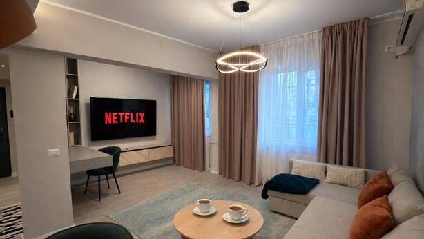 Ein modernes Wohnzimmer mit Flachbildfernseher, einer Couch, einem Couchtisch und einem Essbereich.