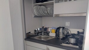 Cocina compacta con lavamanos, estufa y alacenas.