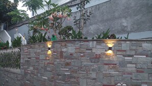 Una pared de piedra con luminarias empotradas, una escalera y diversas plantas.