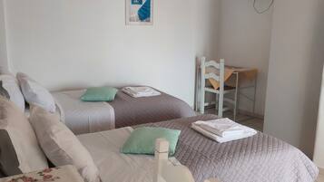 A hotel room with two beds, a TV mounted on the wall, and a small table with a chair.