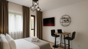 Een hotelkamer met een bed, een televisie, een tafeltje met stoelen en een plank met planten.