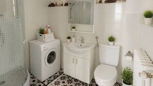 Een badkamer met een wasmachine, wastafel, toilet en douche.