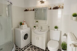 A bathroom with a washing machine, sink, toilet, and shower. - The Warmth Loft | Central Apartment (Bucharest)