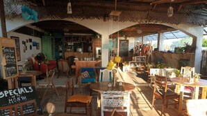 A rustic café with wooden furniture, a chalkboard menu, and a variety of plants.