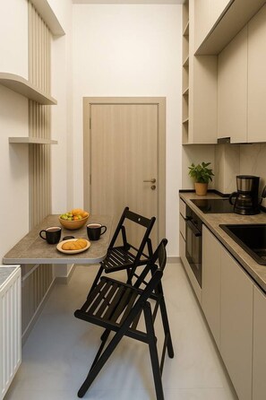 A compact kitchen with a dining area, a door, and a potted plant. - Stylish & Comfortable Studio Retreat (Bucharest)