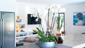 A modern kitchen with a built-in refrigerator, a wooden dining table, and a potted orchid plant.