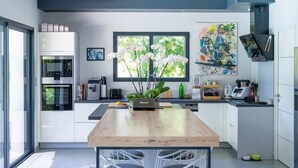 A modern kitchen with a central island, built-in appliances, and a large window.
