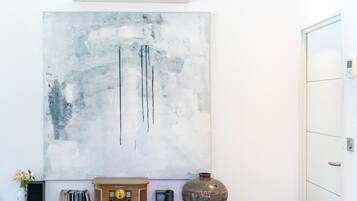 Ein Zimmer mit einem großen, abstrakten Gemälde, einem alten Radio, einer Vase und einer Tür.